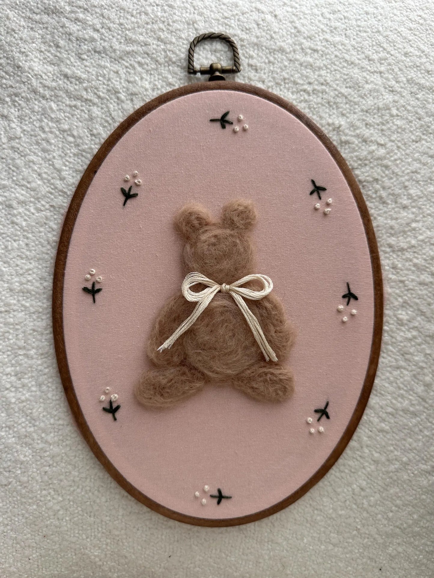 Embroidery hoop with a teddy bear and bow on a pink background
