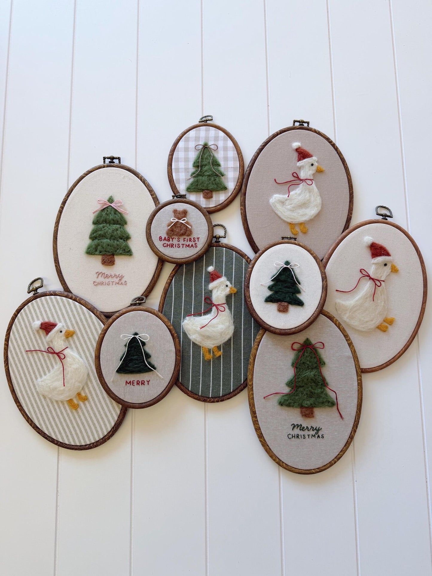 Set of embroidered hoop art with Christmas-themed designs on a white wooden background