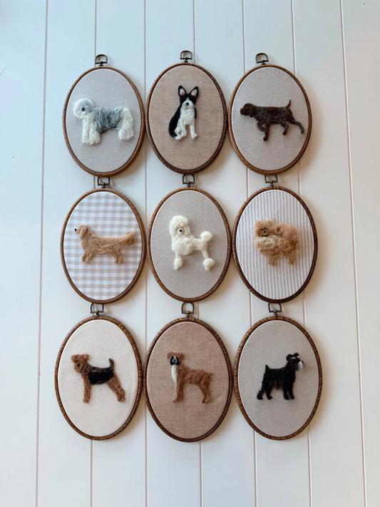 Set of felt embroidered dog portraits in wooden frames on a white wooden panel background