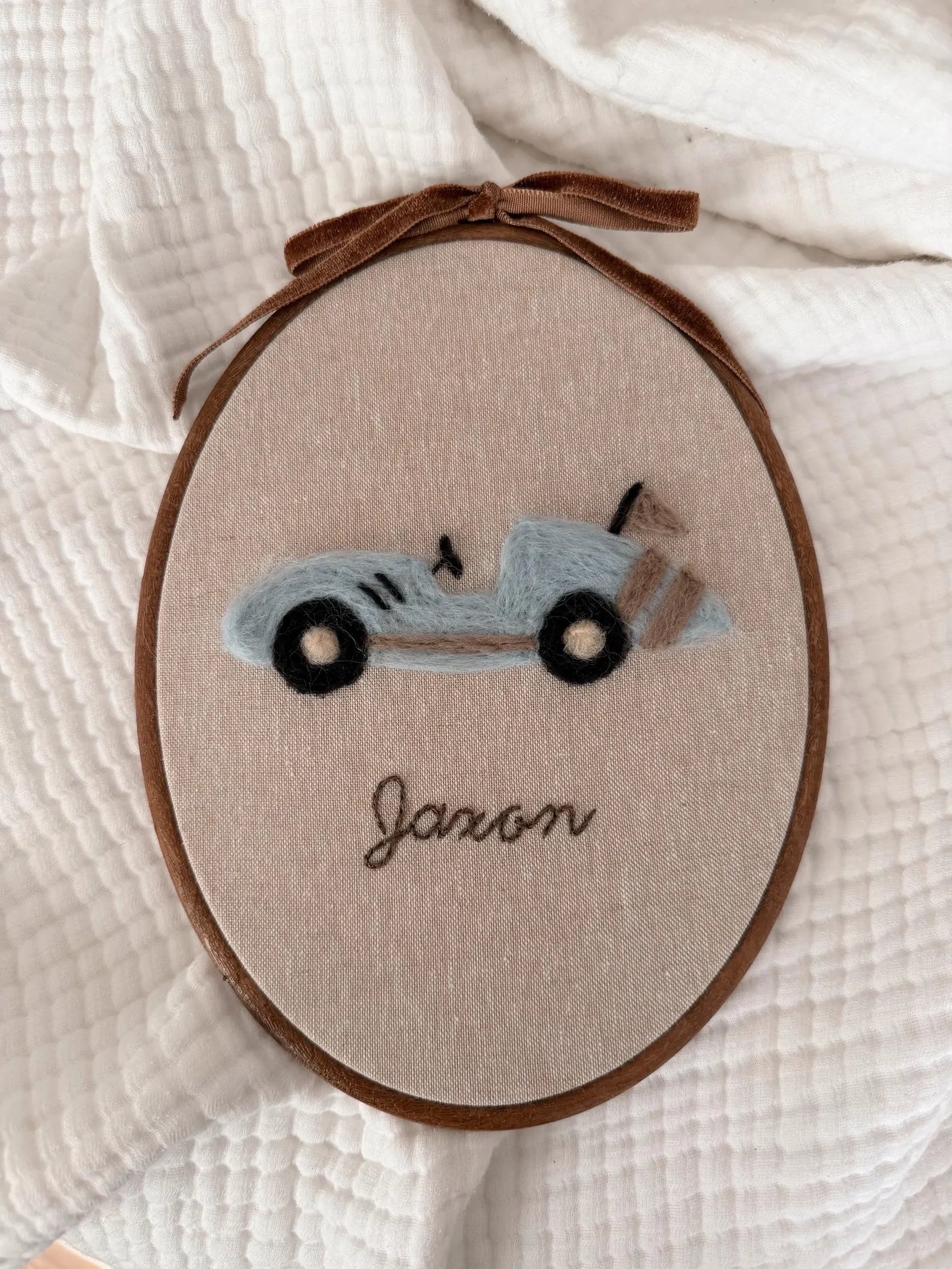 Embroidery hoop with a vintage car design and the name 'Jaxon' on a white fabric background