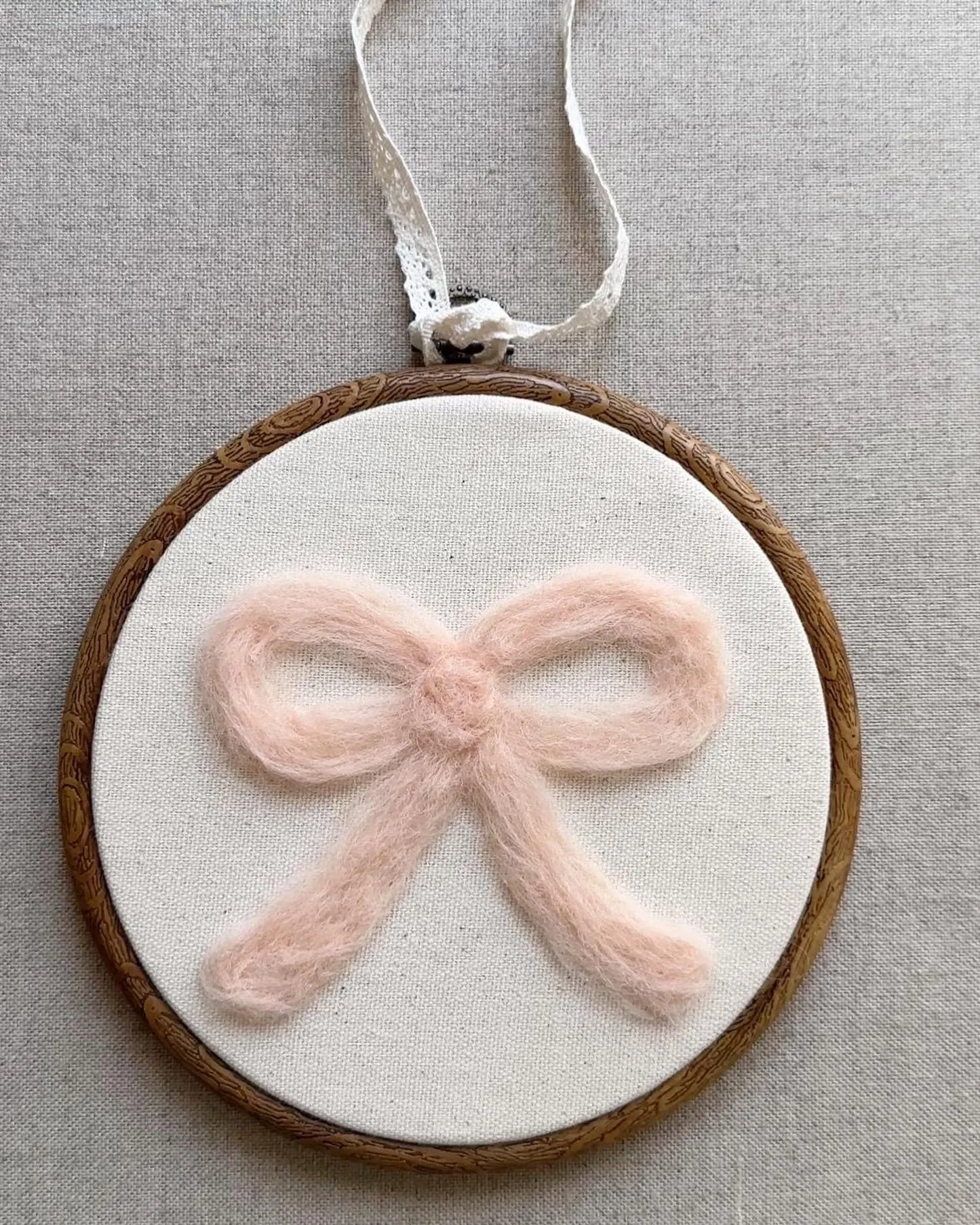 Decorative hoop with a pink bow on a neutral background