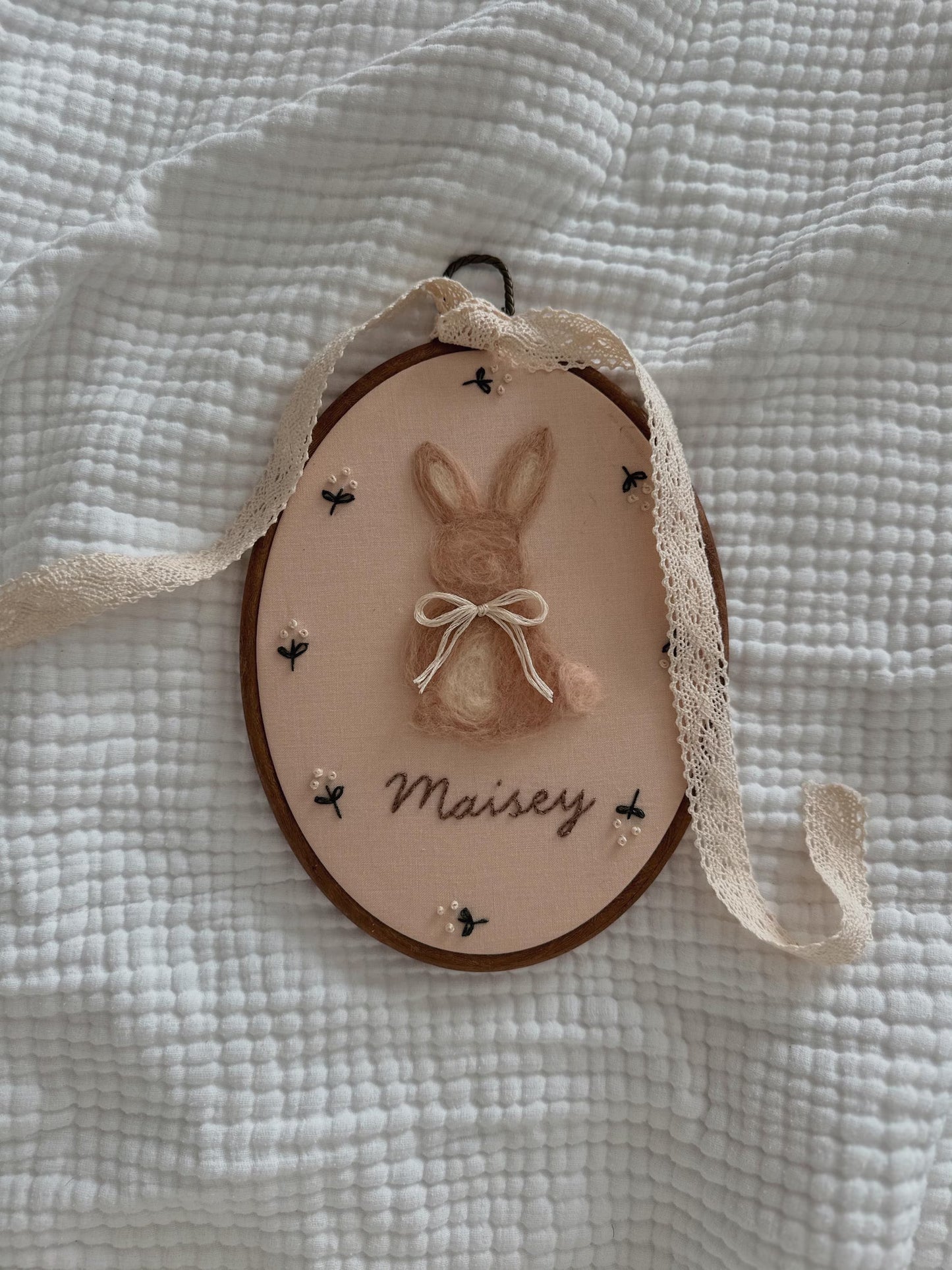 Decorative hanging with a bunny illustration and 'Maisey' text on a textured white background