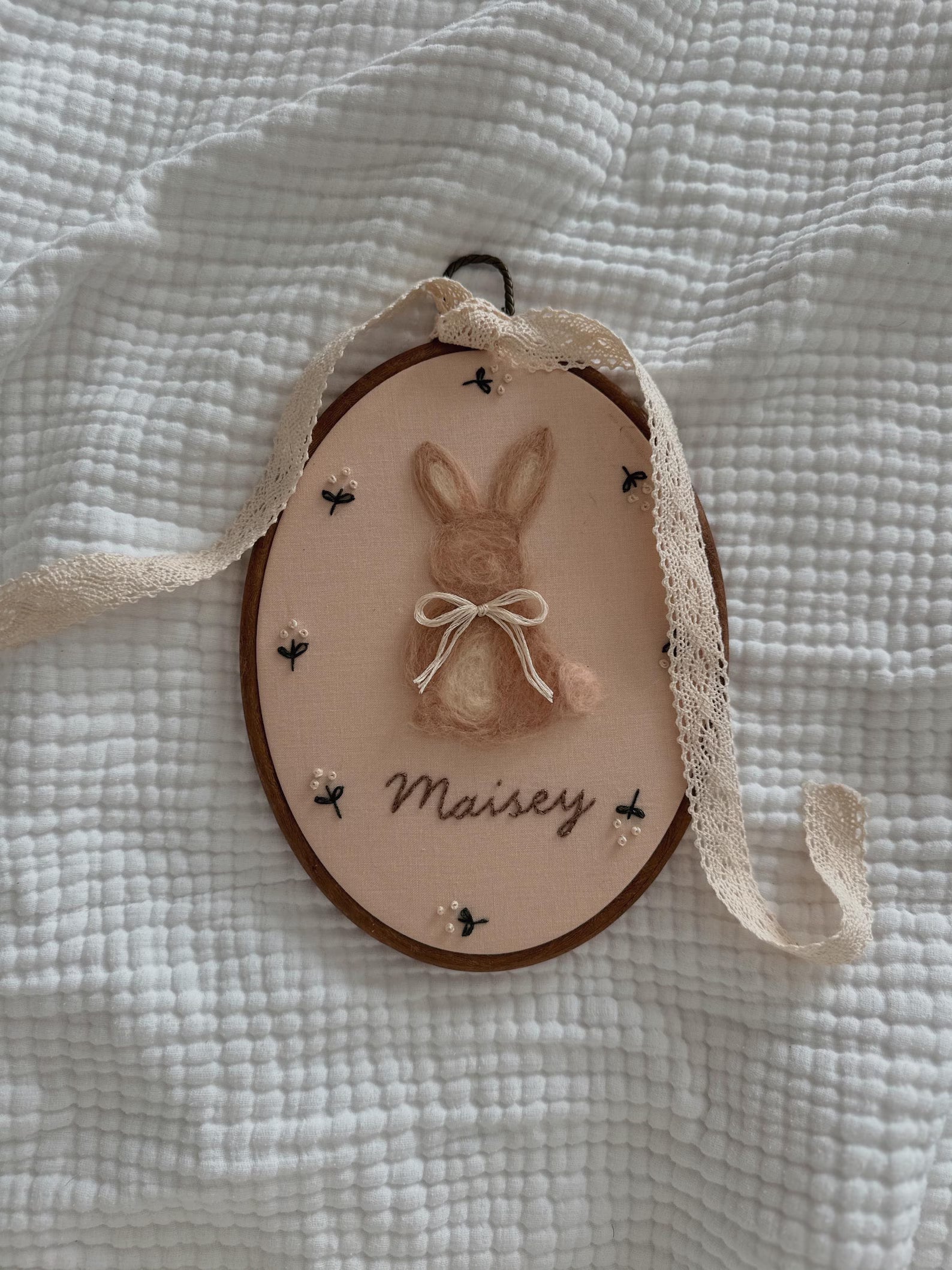 Decorative hanging with a bunny illustration and 'Maisey' text on a textured white background
