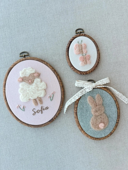 Three embroidered hoop art pieces on a light blue background