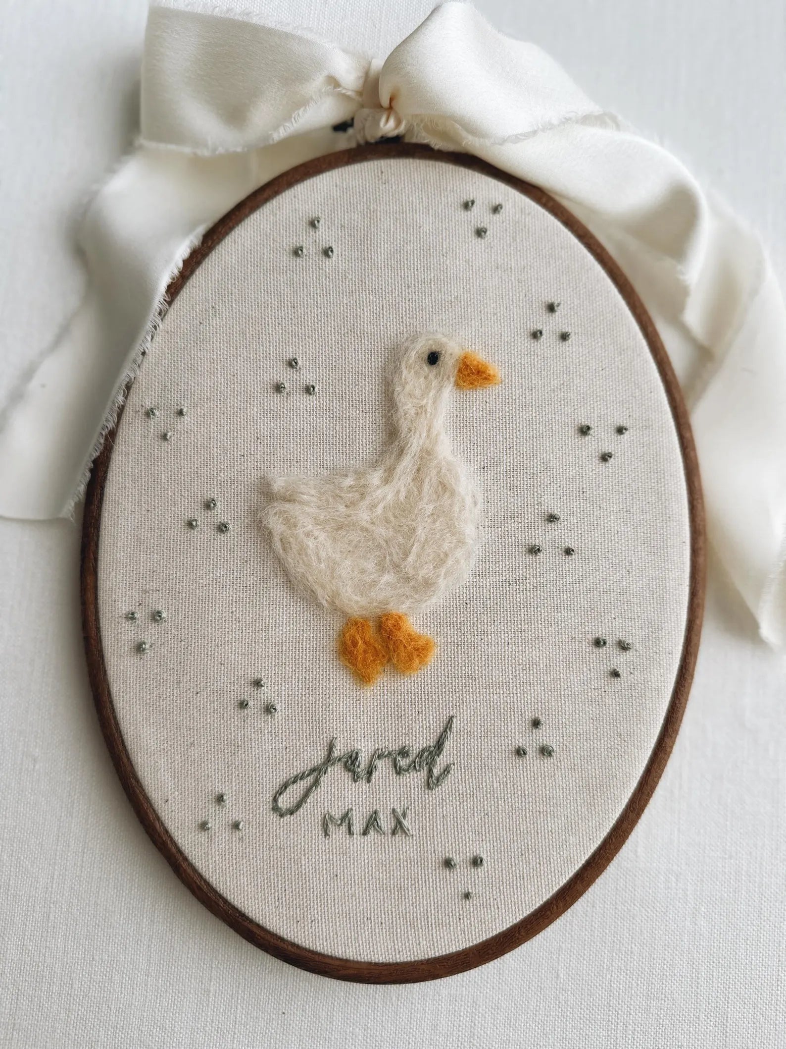 Embroidery hoop with a duck design and embroidered name on a light background
