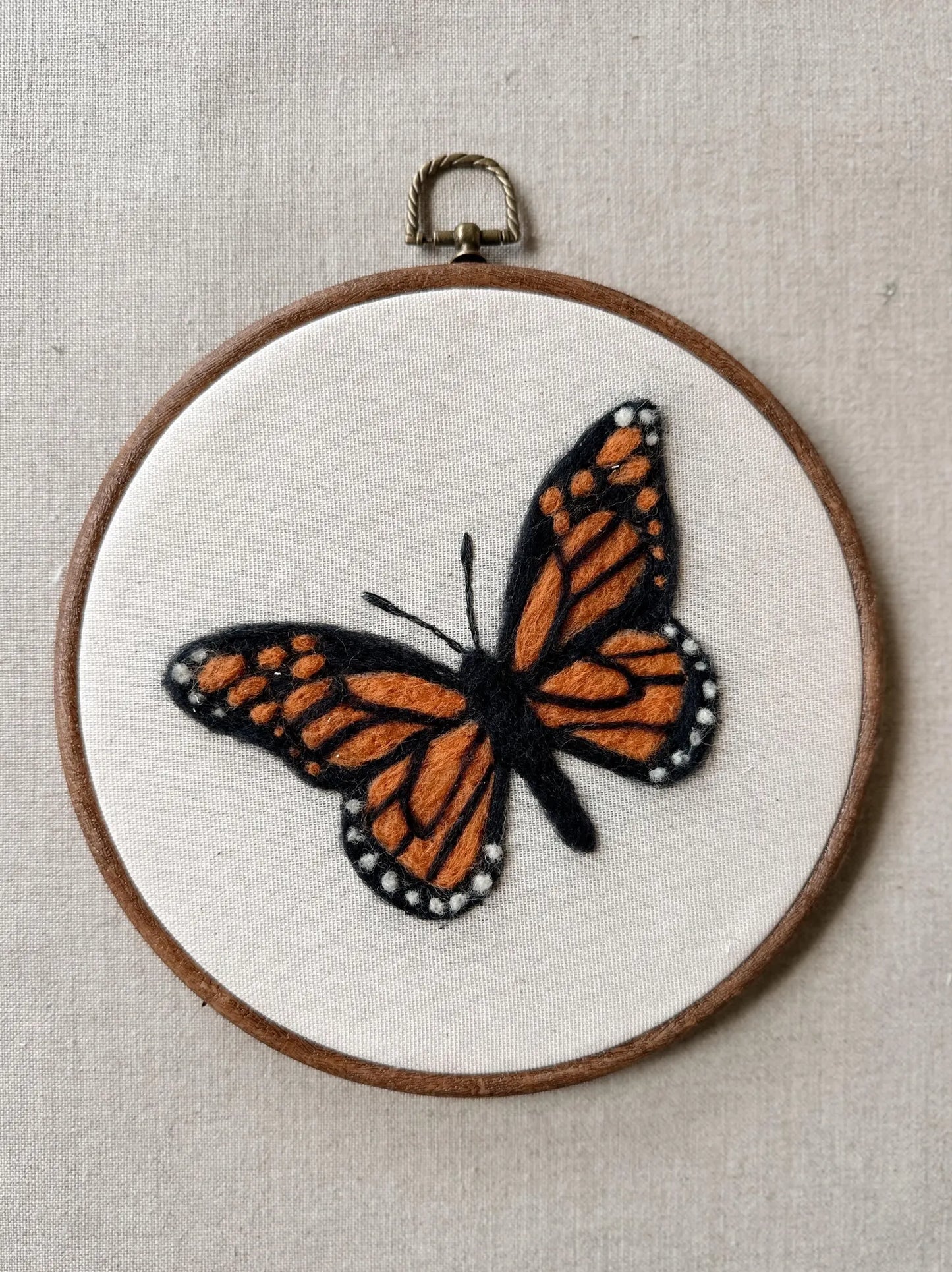 Embroidery hoop with a detailed butterfly design on a beige background