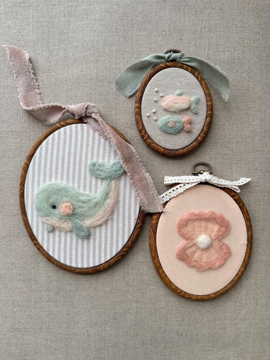 Three embroidered hoop art pieces on a textured fabric background