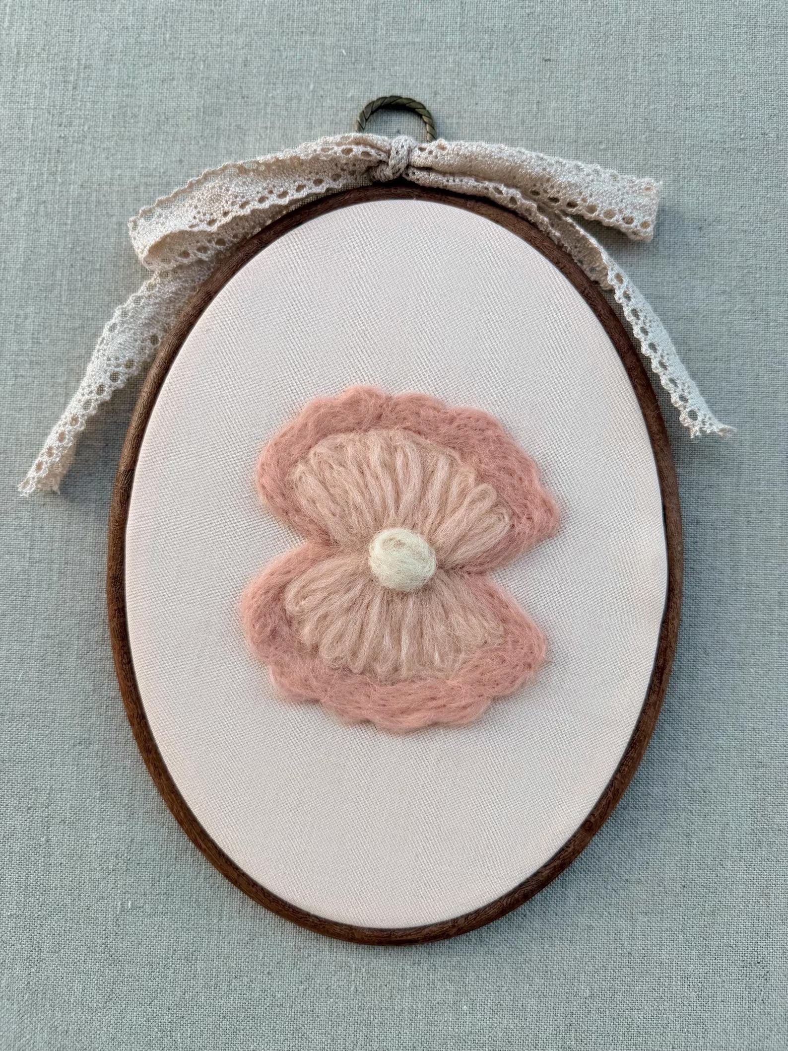Embroidery hoop with a seashell on white fabric against a light blue background