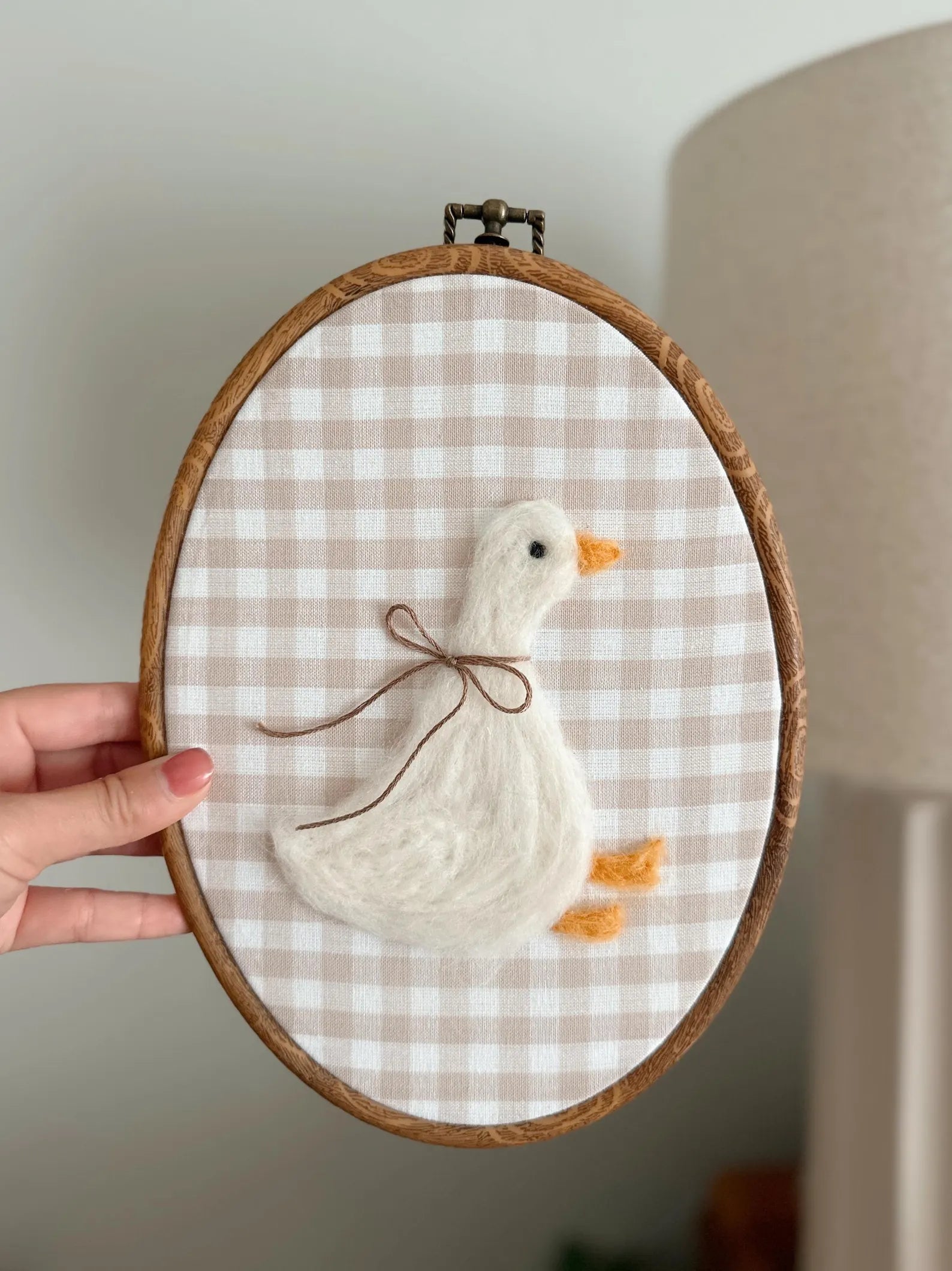 Embroidery hoop with a white duck design on a checkered fabric background