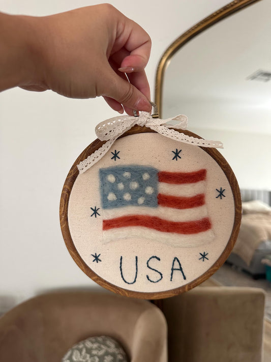 Felted hoop with American flag design and 'USA' text, held by a hand.